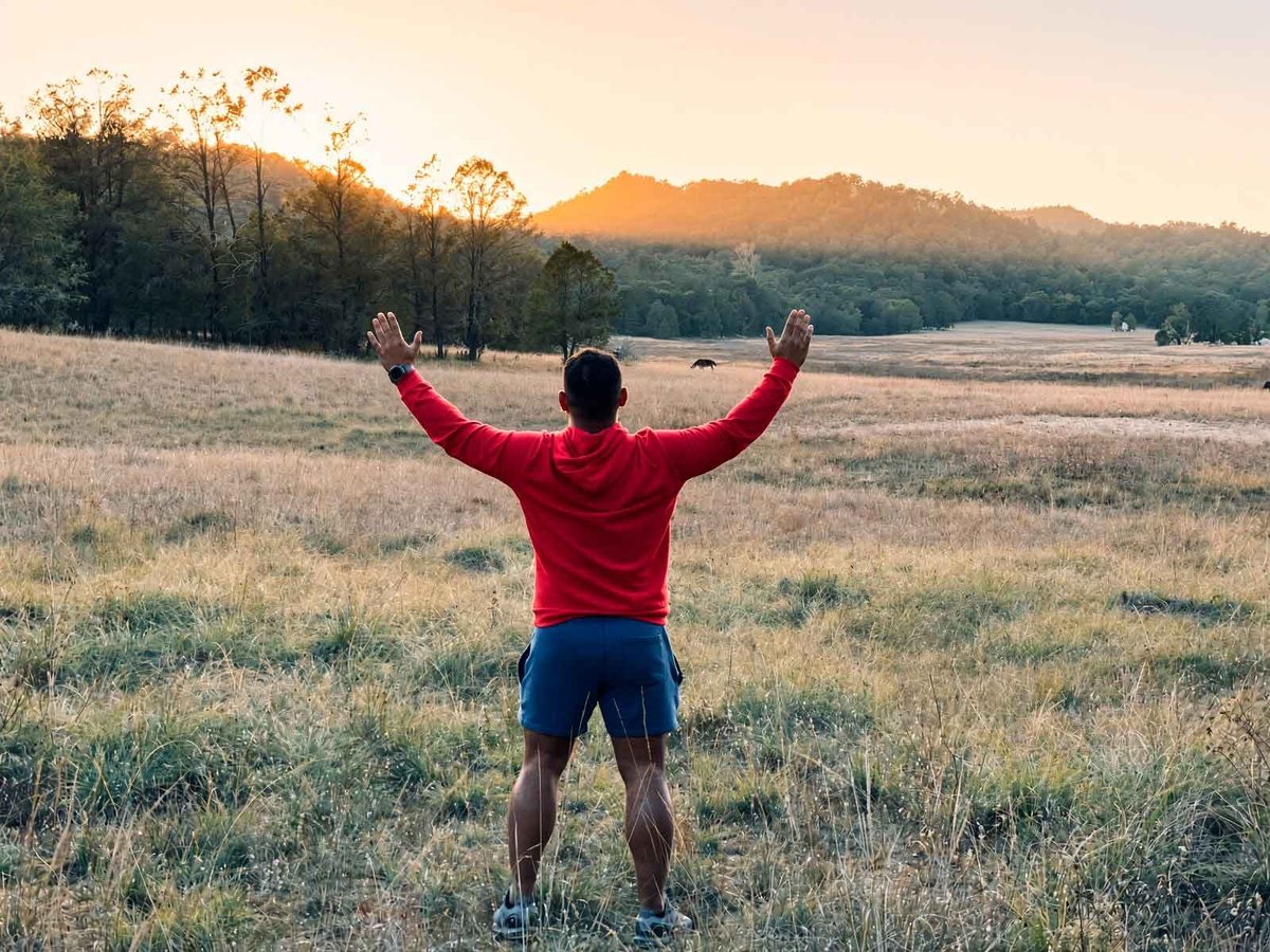 Open valley on the Sierra La Laguna trek, hiker with arms raised facing the mountains