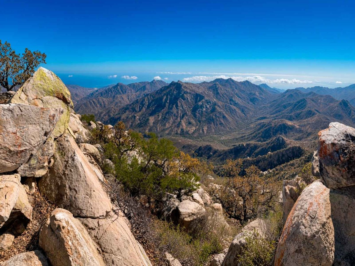 Cresta rocosa del sendero El Puerto con vistas al valle y grandes rocas en primer plano